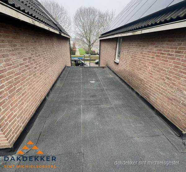 Plat dak met bitumen dakbedekking tussen bakstenen muren in Sint Michielsgestel