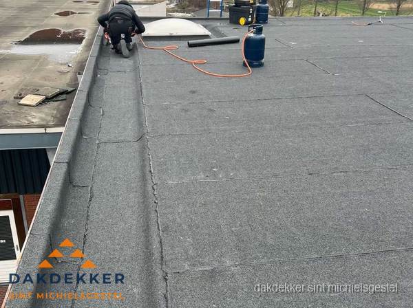 Dakdekker repareert bitumen dakbedekking op groot plat dak in Sint Michielsgestel